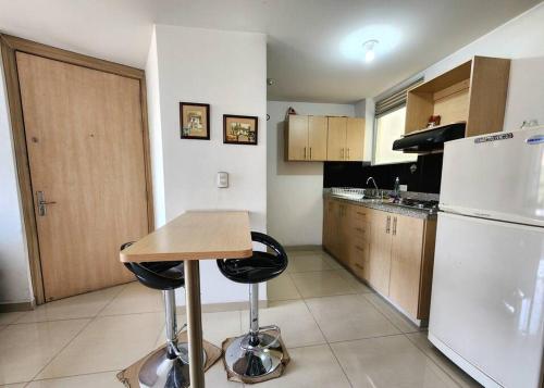 a kitchen with a table and a white refrigerator at Vivienda Céntrica y Acogedora in Sabaneta
