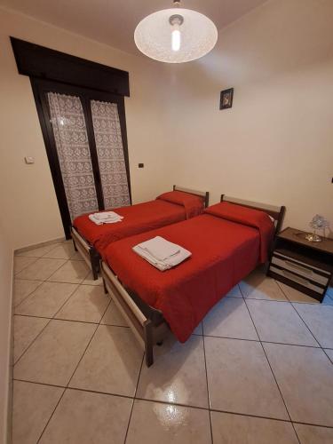 a bedroom with two beds with red sheets and a table at Casa San Francesco in Mondragone