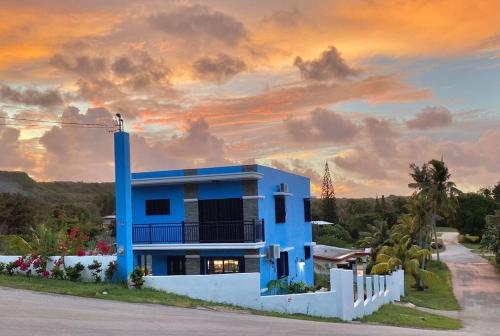 a blue house with a sunset in the background at Entire Property with Patio in Yona