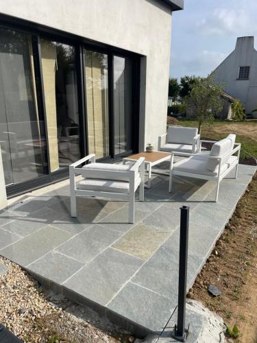 three white chairs and a table on a patio at Ti Nolgann in Lannilis