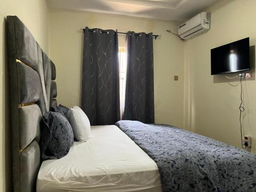 a bedroom with a bed and a window and a television at YP-Made Luxurious 1 & 2 Bedroom Apartments in Eluju