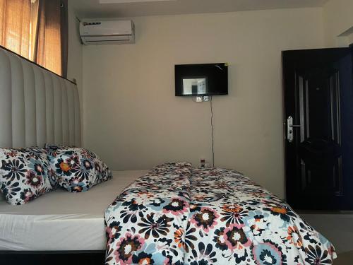 a bedroom with a bed with a floral comforter and a television at YP-Made Luxurious 1 & 2 Bedroom Apartments in Eluju