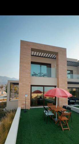a house with a table and chairs and an umbrella at Naseem AlBahar in Muscat