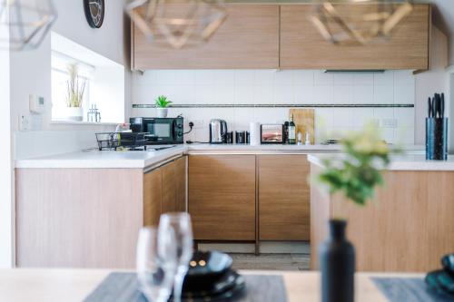 a kitchen with wooden cabinets and a table with wine glasses at Luxury City Stay Coop Live & Etihad with Free Parking in Manchester