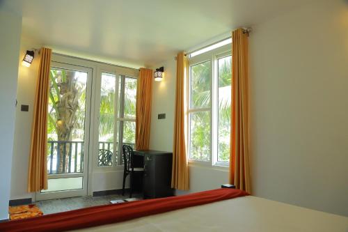 a bedroom with a bed and two windows and a desk at Lakefront Beach Homes in Cherai Beach