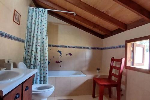 a bathroom with a tub and a toilet and a chair at Family home, panoramic views of lake & countryside in Puerto Rico