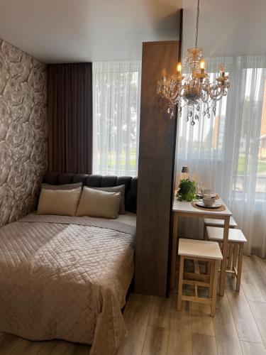 a bedroom with a bed and a table and a chandelier at Chic Residence apartament 2 in Šiauliai