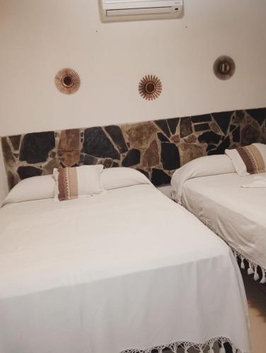 two beds in a room with a stone wall at Grann Posada Xilitla in Xilitla