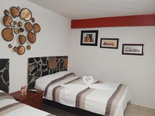 a hotel room with two beds and a clock on the wall at Grann Posada Xilitla in Xilitla