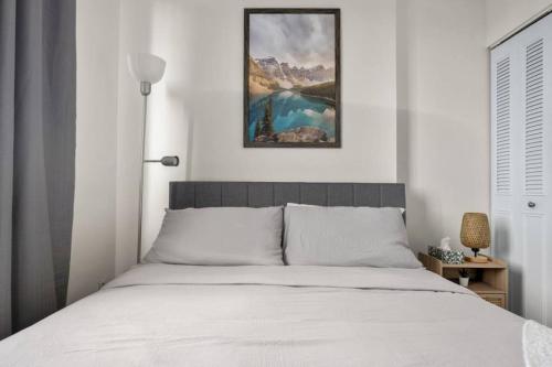 a bed in a bedroom with a picture on the wall at Downtown Near Rogers Place with Covered Parking, Sleeps 6, Pool Table, Sauna, Gym, Two Bedrooms & More in Edmonton