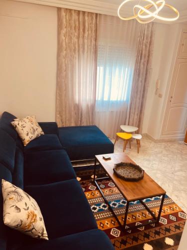Borj TurkiにあるEnnasr, Apt très bien équipé, central et paisibleの青いソファとテーブルのあるリビングルーム