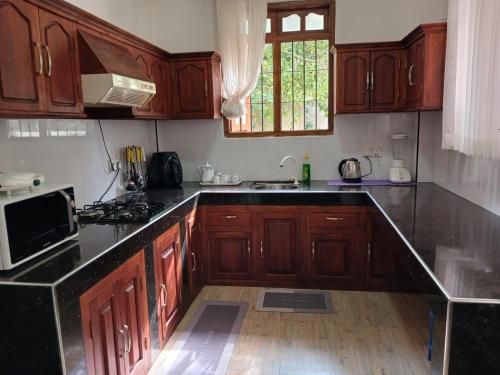 a kitchen with wooden cabinets and a black counter top at Ella Aman Vanicia Resort in Ella