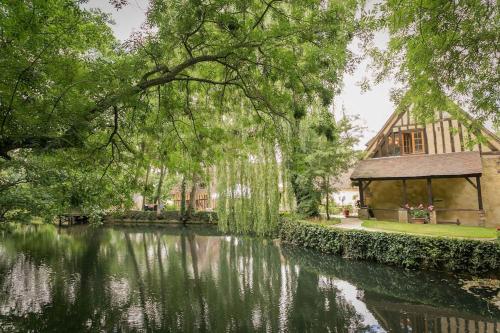 a house next to a river with a building at Gîte du Moulin rouge in Vernouillet