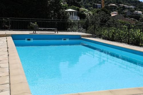 une piscine bleue avec un banc à côté d'une clôture dans l'établissement Haut de villa vue mer panoramique sur Golfe de Saint-Tropez, aux Issambres