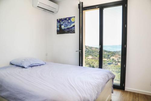 une chambre avec un lit et une grande fenêtre dans l'établissement Haut de villa vue mer panoramique sur Golfe de Saint-Tropez, aux Issambres