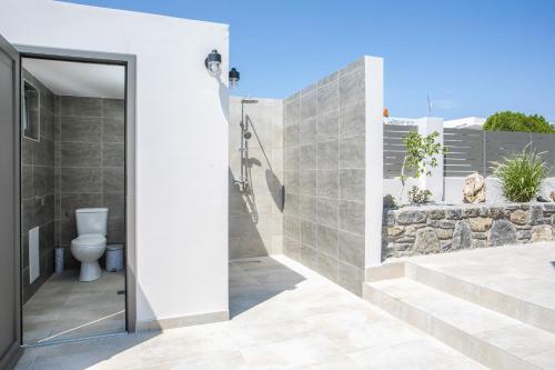 a bathroom with a toilet and a stone wall at Maro Luxury Villa in Afantou