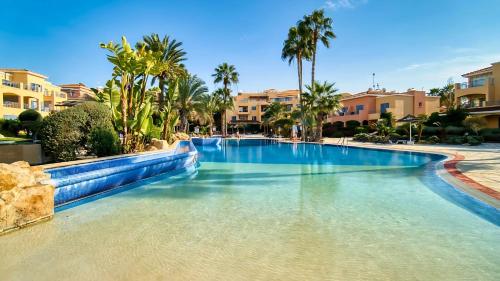 a swimming pool in a resort with palm trees and buildings at Agapi Apartment Limnaria Gardens near Paphos Harbour & Beach in Paphos
