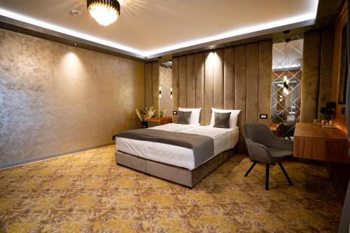 a hotel room with a bed and a chair at Hanul Domnesc Imperial Hotel & SPA in Călan