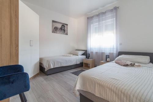 a bedroom with two beds and a blue chair at Villa Nicolle in Privlaka