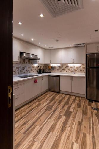 a large kitchen with white cabinets and wooden floors at جناح خاص في أجنحة طيبة in Al Madinah
