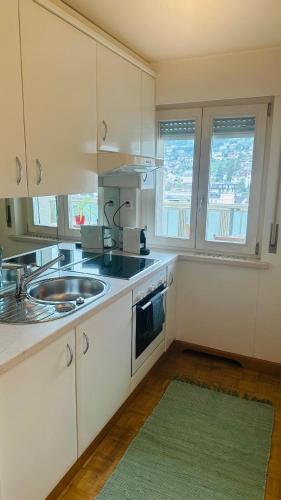 a kitchen with white cabinets and a sink and two windows at Casino Montreux Lac in Montreux