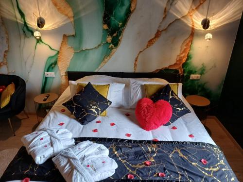 a bed with a red heart pillow on it at Bélénos - Suites & Spa in Bligny-sur-Ouche