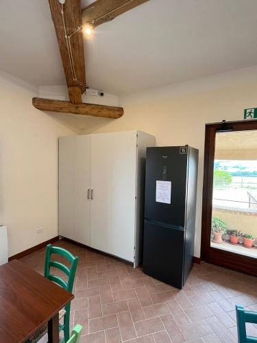 a kitchen with a black refrigerator and a table at Affittacamere Podere Valserena in Monteroni dʼArbia