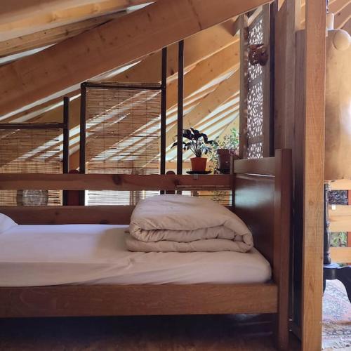 un lit avec un cadre en bois dans une chambre dans l'établissement Grande YOURTE dans les jardins d'Amagaïa, à Boulc