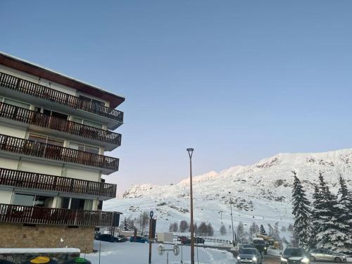 a building with a snow covered mountain in the background at Appartement Concorde MoonTain - Face aux pistes - Central in L'Alpe-d'Huez