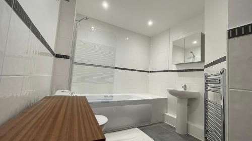 a white bathroom with a sink and a toilet at 4- bedroom , 1 living room Apartment Near Emirates Stadium in London