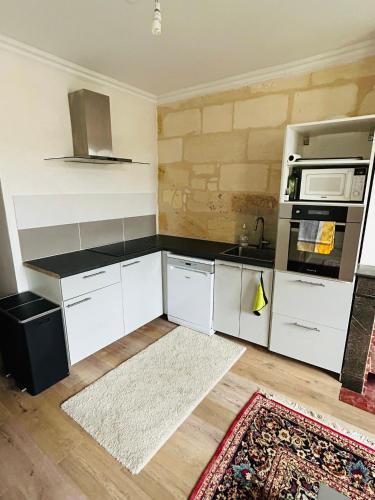 une cuisine avec des armoires blanches et un comptoir noir dans l'établissement Appartement Duplex - 2 Chambres - Cosy & Spacieux-, à Bordeaux