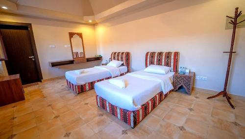 Una habitación de hotel con dos camas y un espejo. en Desert Rose Camp, en Badīyah