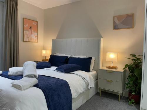 a bedroom with a large bed with blue pillows at Luxury Apartment in Olympic Village in London