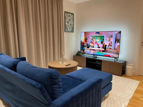 a living room with a blue couch and a tv at Luxury Apartment in Olympic Village in London