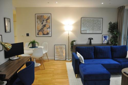 a living room with a blue couch and a table at Luxury Apartment in Olympic Village in London