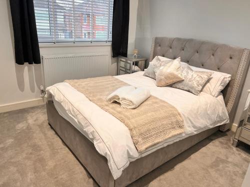 una habitación con una cama grande con sábanas y almohadas blancas en Luxury Modern Spacious House, en Hull