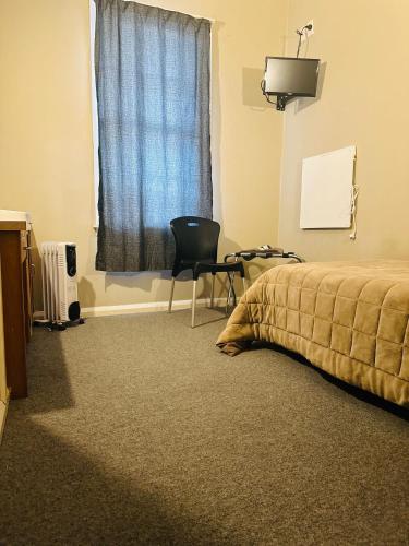 a bedroom with a bed and a chair and a window at Merrylees Hotel in Dannevirke