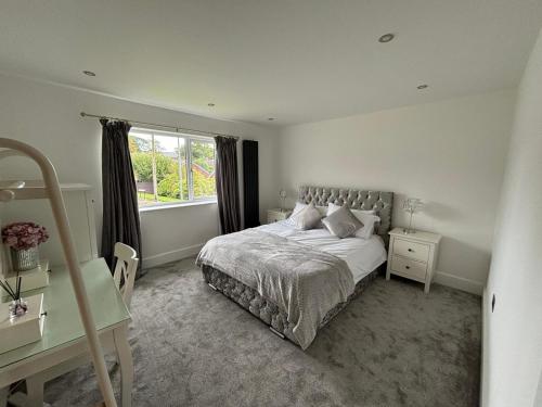 a bedroom with a bed and a desk and a window at Newly Refurbished Tor View Executive Dormer Bungalow Rossendale in Haslingden