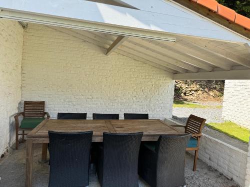 a wooden table and chairs under a roof at Maison privative dans un environnement idyllique in Lasne