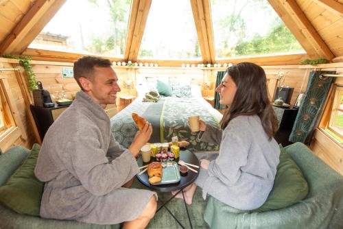 a man and woman eating food in a tiny house at La Bulle de Chantilly - Spa & sauna privatifs & petit déjeuner gourmand in Saint-Leu-dʼEsserent