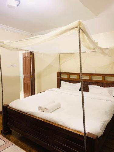 a bedroom with a canopy bed with white towels on it at Tevody Heights in Nairobi