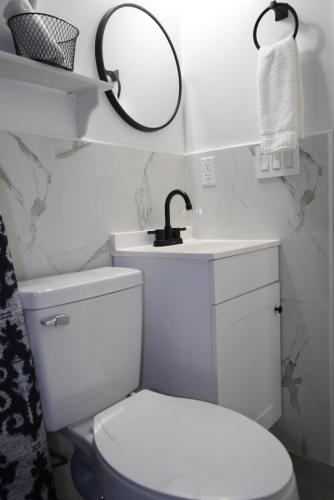 a bathroom with a white toilet and a mirror at Luxury apartment 1 in Tampa