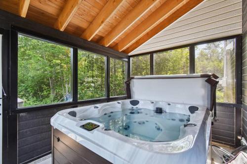 a large tub in a room with windows at Chalet Astra in Mandeville