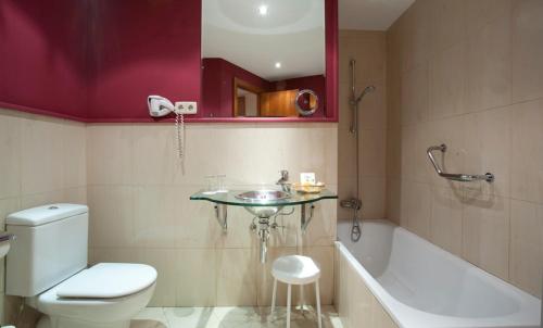 a bathroom with a toilet and a sink and a tub at Ateneo Puerta del Sol in Madrid