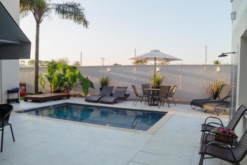 a swimming pool with chairs and a table and an umbrella at Hotel e Pousada VIVÁ in Chapada dos Guimarães