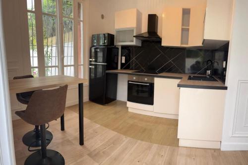 cocina con mesa de madera y nevera negra en Appartement avec jardin C, en Nogent-sur-Marne
