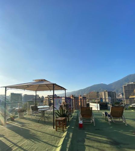 a patio with chairs and an umbrella on a roof at Ololó Caracas B&B in Chacao