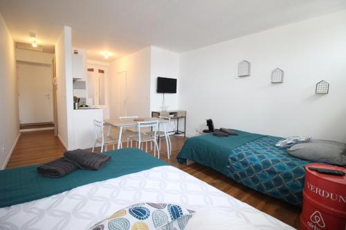 - 2 lits dans une chambre avec une cuisine et une table dans l'établissement Chez Marie et Geneviève - Verdun Centre - STUDIO - 2 GRANDS LITS - Géré par Presta-Zen'Services, à Verdun-sur-Meuse