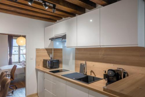 une cuisine avec des armoires blanches et un évier dans l'établissement ORLEANS CENTRE HISTORIQUE - Charmant T2 - L'EVASION ORLEANAISE, à Orléans