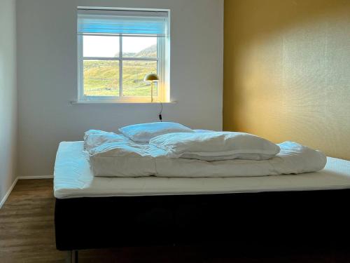 a bed with white sheets and a window in a room at Modern Vacation Home With Hot Tub in Froðba